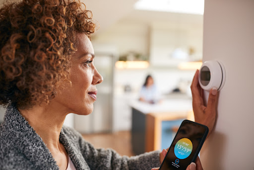 Woman adjusting thermostat while checking the app to see why her furnace is running constantly.