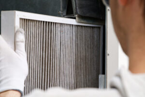 A person with gloves replacing an HVAC air filter.