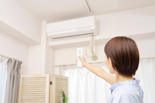Woman turning on indoor AC using remote.