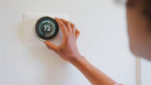Homeowner adjusting thermostat to 72 degrees.